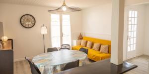 a living room with a table and a yellow couch at villa Hortense in Saint-Martin-de-Ré +3 photos