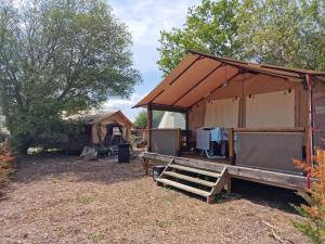 a tent with a table and a bench in a yard at Lodge Les P'tites Maisons dans la Prairie in Sallertaine