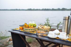 a picnic table with food and drinks on it next to the water at Leopard Trails Wilpattu in Wilpattu