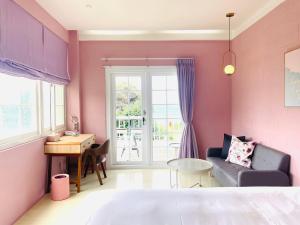 a pink room with a couch and a table at Canaan B&B Kenting in Eluan