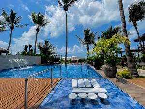 a pool with white lounge chairs and palm trees at Wassu Pousada in São Miguel dos Milagres