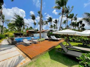 - une terrasse en bois avec des chaises et des parasols à côté de la piscine dans l'établissement Wassu Pousada, à São Miguel dos Milagres