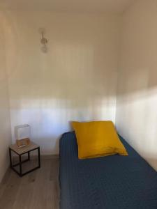 Appartement 2 pièces de 29 m2 في كان: سرير مع وسادة صفراء وطاولة جانبية