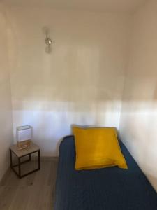 Appartement 2 pièces de 29 m2 في كان: سرير مع وسادة صفراء وطاولة جانبية