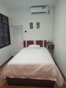 1 dormitorio con 1 cama blanca grande. en Hotel Berlian en Pontianak