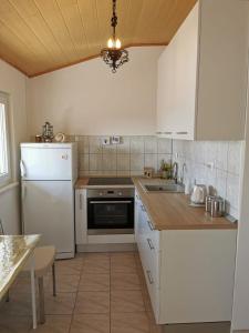 a kitchen with white cabinets and a sink and a refrigerator at Apartmani Vana 1 in Tribunj +9 photos