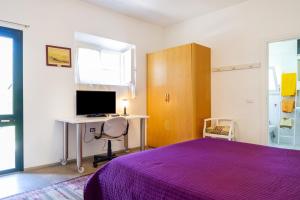 - une chambre avec un lit violet et un bureau avec un ordinateur dans l'établissement Casina Orbetello, à Orbetello