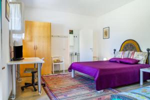 - une chambre avec un lit violet et un bureau dans l'établissement Casina Orbetello, à Orbetello