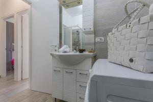 uma casa de banho branca com um lavatório e um espelho em Lido degli Estensi Seaview Apartment em Lido degli Estensi