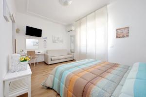 a white bedroom with a bed and a chair at B&B Felicioni in Fiumicino
