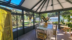 a conservatory with a table with a vase of flowers on it at Maison charmante au Thor + Piscine in Le Thor