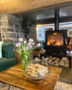 a table with a bowl of cookies and a fireplace at Three Cocks Hotel in Brecon