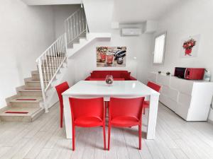 una sala da pranzo con tavolo bianco e sedie rosse di Villa Roberta Spiaggiabianca Deluxe - A 20 metri dal mare a San Pietro in Bevagna