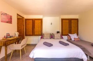 a bedroom with a bed and a desk and windows at Le Mas de Riri in Celles
