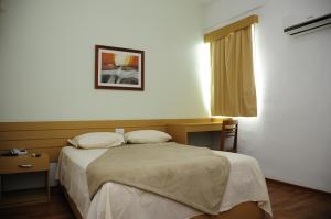 a bedroom with a bed and a desk and a window at Hotel Family São Paulo - No Shopping FAMILY - No Brás in São Paulo