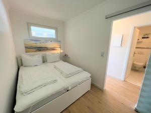 a bedroom with a bed with white sheets and a window at Ferienpark Sierksdorf App 793 - Lillis Oase in Sierksdorf