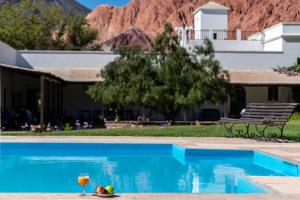 a glass of wine and fruit next to a swimming pool at Hotel El Manantial del Silencio in Purmamarca