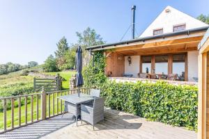 a wooden deck with a table and a house at The Old Barn - cottage with spectacular lake view in Port of Menteith