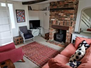 a living room with a brick fireplace and a red couch at Beggar's Lane Cottage in Winchester