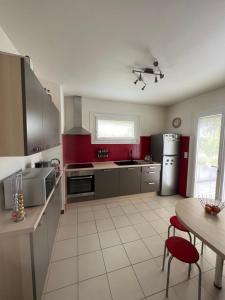 a kitchen with red walls and stainless steel appliances at Les Mazades à 10 min de Périgueux avec piscine chauffée, meublé de tourisme classé 3 étoiles in Annesse-et-Beaulieu