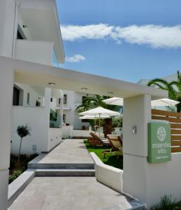 a white house with chairs and umbrellas on a patio at Essentia Vita Comfy Suites in Limenas