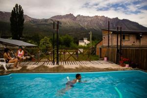a young boy swimming in a swimming pool with mountains in the background at Las Quintas El Bolsón in El Bolsón