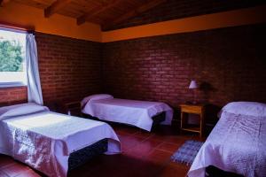 a room with two beds and a brick wall at Las Quintas El Bolsón in El Bolsón