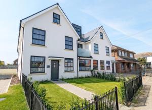 una casa bianca con una recinzione di Pebblestone a East Wittering