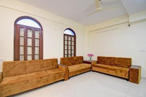 ein Wohnzimmer mit zwei braunen Sofas und zwei Fenstern in der Unterkunft Super Townhouse 1109 Jheel Mahal in Jojera