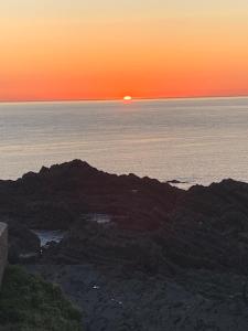 zachód słońca nad oceanem z zachodem słońca na horyzoncie w obiekcie Home from Home B&B w mieście Hartland