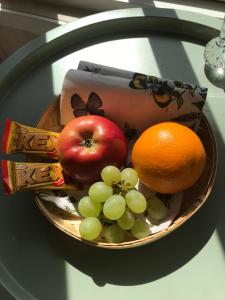 a bowl of fruit with an apple oranges and grapes at Backahusets B&B in Höör