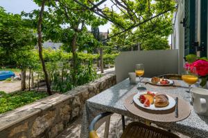 una mesa con un plato de comida y vasos de zumo de naranja en Villa Doris, en Zaton