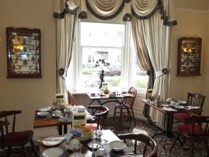 a dining room with tables and chairs and a window at The Cumberland in Llandudno