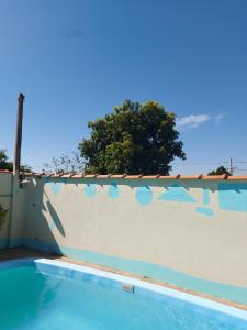 a swimming pool next to a white wall at Acordar com o cantar do passaro in Jabuticabal