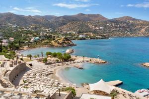 a view of a beach with chairs and the ocean at Wyndham Grand Crete Mirabello Bay in Agios Nikolaos