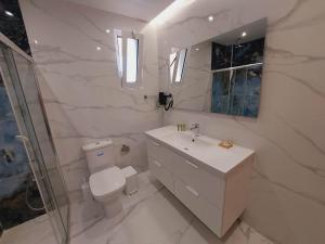 a white bathroom with a toilet and a sink at Sapphire home in Ixia