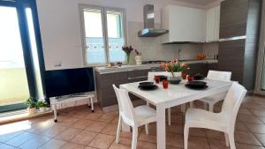 eine Küche mit einem weißen Tisch und Stühlen sowie einem TV in der Unterkunft Apartment SunShine in Marzamemi