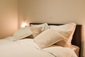 una cama con almohadas blancas encima en Miramar Residences - Luxurious Seaside Apartments, en Blankenberge