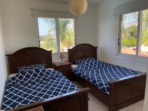 two beds in a bedroom with two windows at Coral Bay new furnished private villa with pool in Peyia