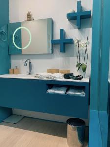 een blauwe badkamer met een wastafel en een spiegel bij Casa Nausica in Acitrezza