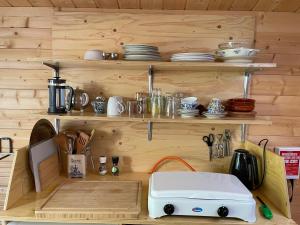 a kitchen with wooden walls and shelves with a toaster at VierVaart Veldhuisje MOS in Groede