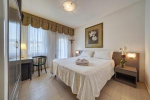 a hotel room with a bed and a desk and a window at Hotel Terme Olympia in Montegrotto Terme