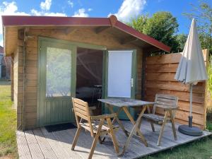 a wooden cabin with a table and chairs and an umbrella at VierVaart Veldhuisje MOS in Groede
