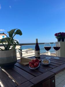 een houten tafel met twee glazen wijn en fruit bij Apartment SunShine in Marzamemi