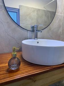 a bathroom sink with a large round mirror and a sink at le moringa Appart vue mer 360 Mamoudzou hyper centre in Mamoudzou