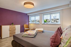two beds in a room with purple walls and windows at Helms in Eriskirch