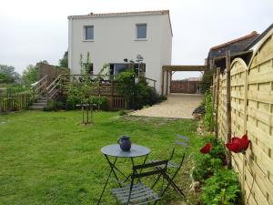 een tafel en stoelen in een tuin met een huis bij LA PETITE SALAMANDRE des Conches in Longeville-sur-Mer