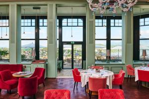 ein Restaurant mit roten Stühlen, Tischen und Fenstern in der Unterkunft Château Gütsch in Luzern