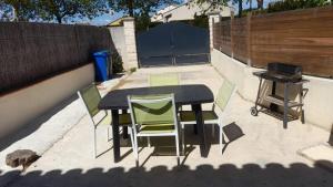 een tafel en stoelen op een patio met een grill bij Le Chant des Cigales in Le Cailar