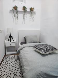 een slaapkamer met een bed en een witte muur bij Apartment Andy in Zagreb